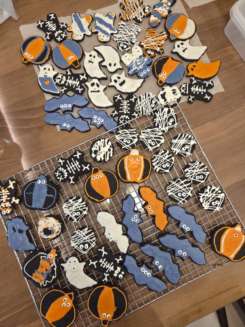 The whole batch of hand-decorated Halloween cookies on baking paper and a cooling rack